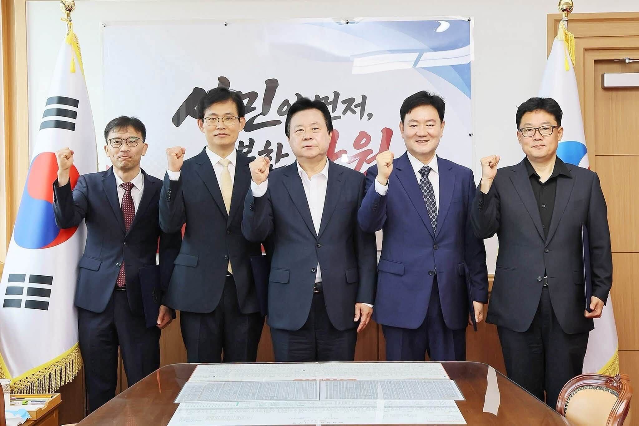 창원시 감사관 임명식 — 태극기와 시 상징기 사이, 다섯 분이 주먹을 쥐고 포즈